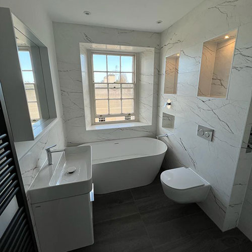 After picture of a customer bathroom with marble effect tiles and a modern white bathroom suite